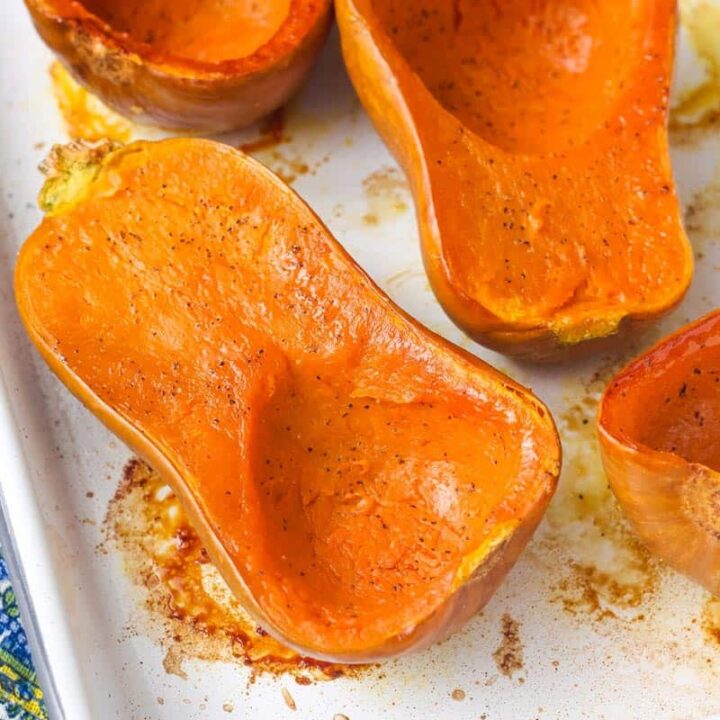 Roasted honeynut squash halves on a small sheet pan.