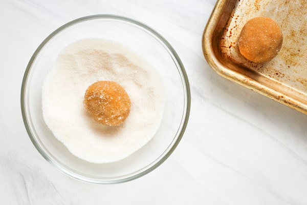 Ball of cookie dough in a bowl of granulated sugar.