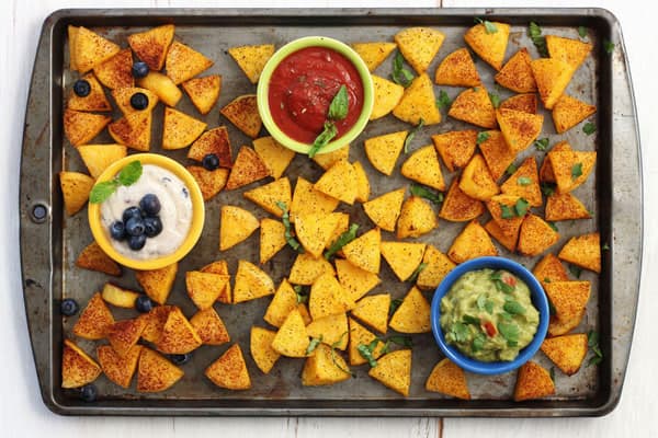 A variety of cooked polenta wedges on a pan with small bowls of yogurt, marinara, and guacamole.
