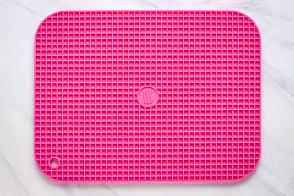 Close up of a bright pink 9 x 12 silicone trivet.