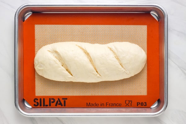 Unbaked loaf of dough with three slash marks across the top.