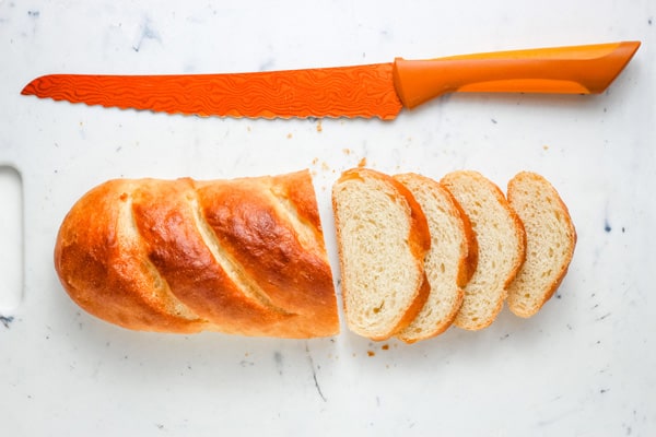 Sliced small baguette next to a bread knife.