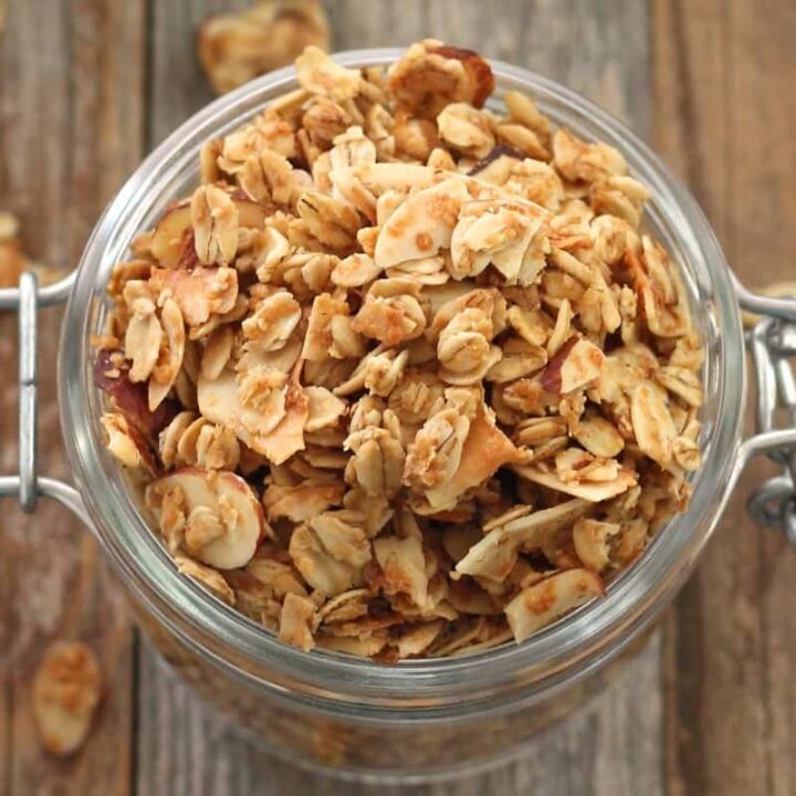 Closeup of flaky granola in a small glass jar.