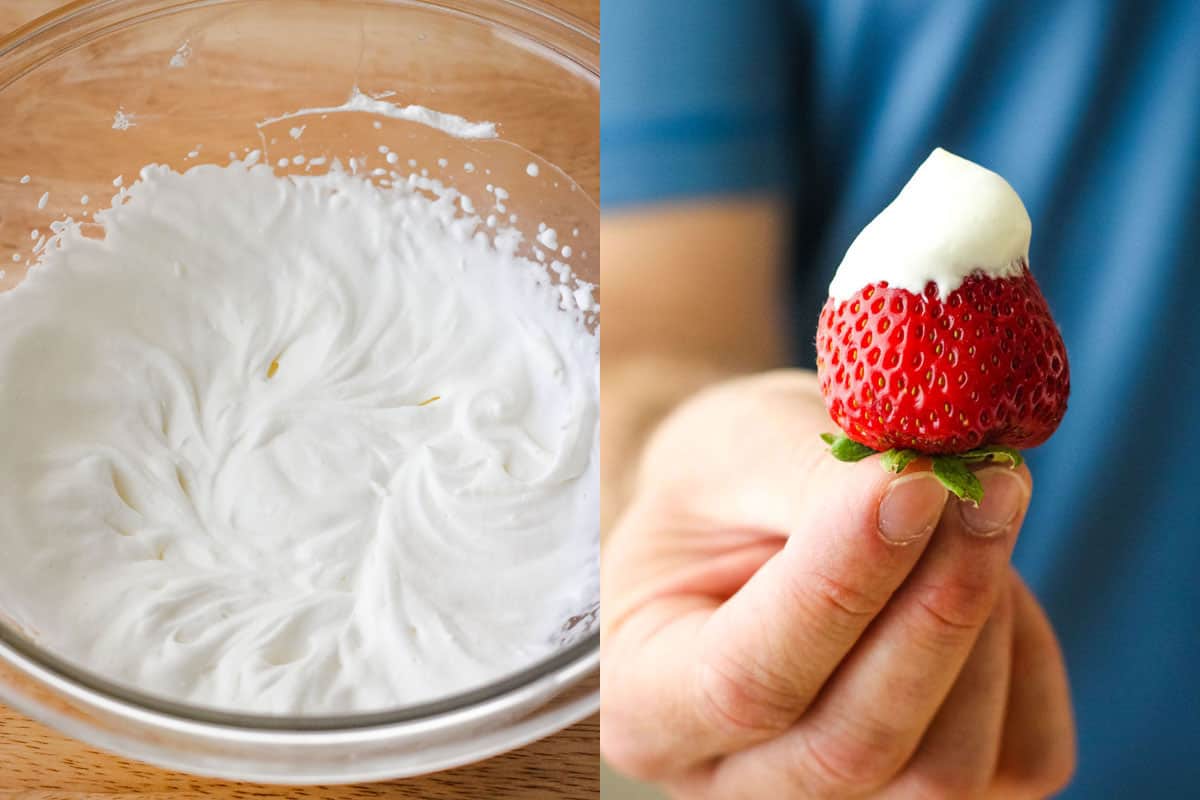 Glass bowl of fluffy whipped cream and hand holding a juicy red strawberry topped with whipped cream.