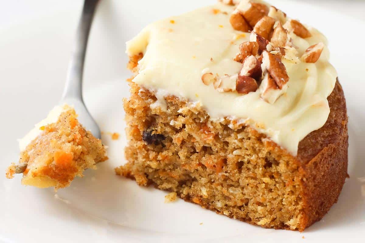 Closeup of carrot cake slice showing tender cake, raisins, and shredded carrots.