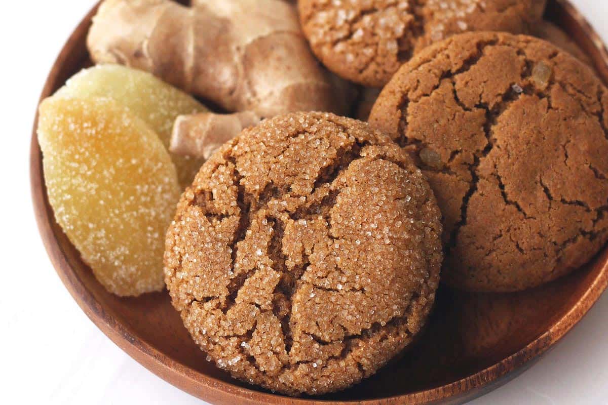 Closeup of baked ginger cookies in a bowl with fresh and candied ginger.