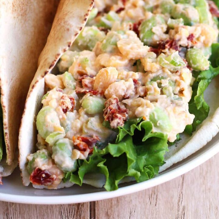 Closeup of chickpea salad wrapped in a pita on a plate.