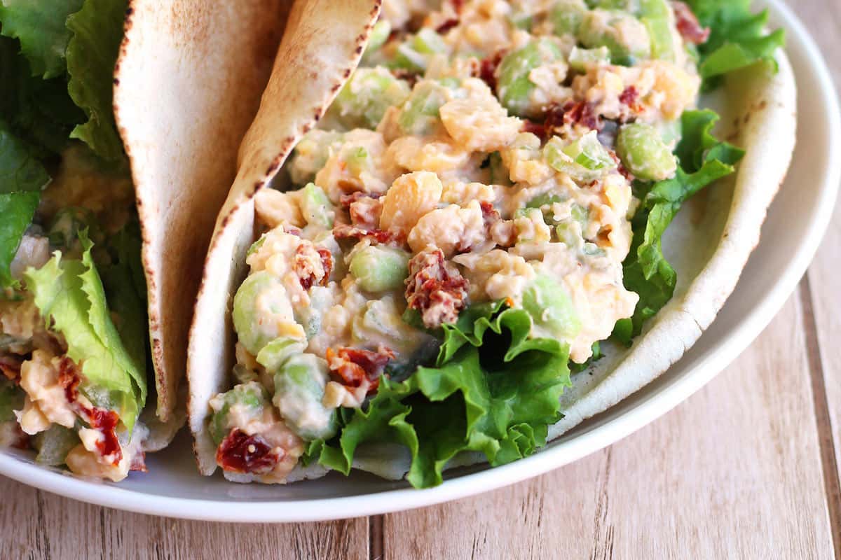 Closeup of chickpea salad wrapped in a pita on a plate.