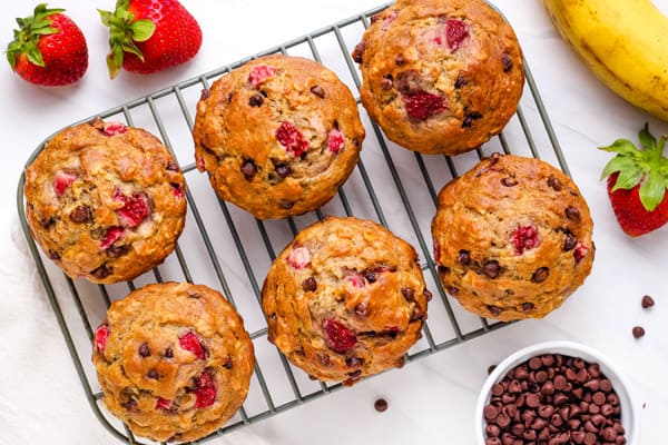 Strawberry banana oat muffins with chocolate chips on a baking rack.