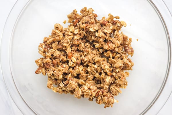 Overhead view of buttery crumble topping in a glass bowl.