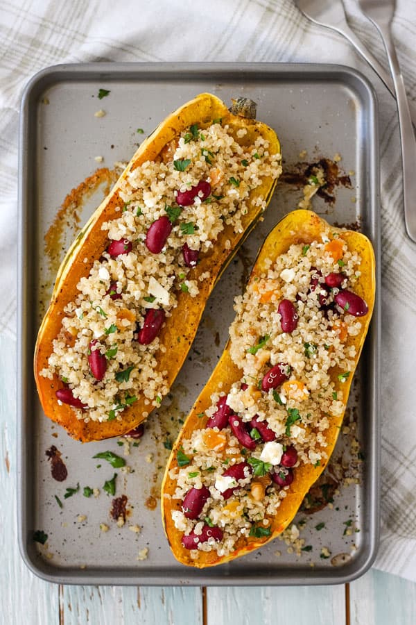 Two delicata squash boats stuffed with a quinoa salad on a toaster oven baking sheet.
