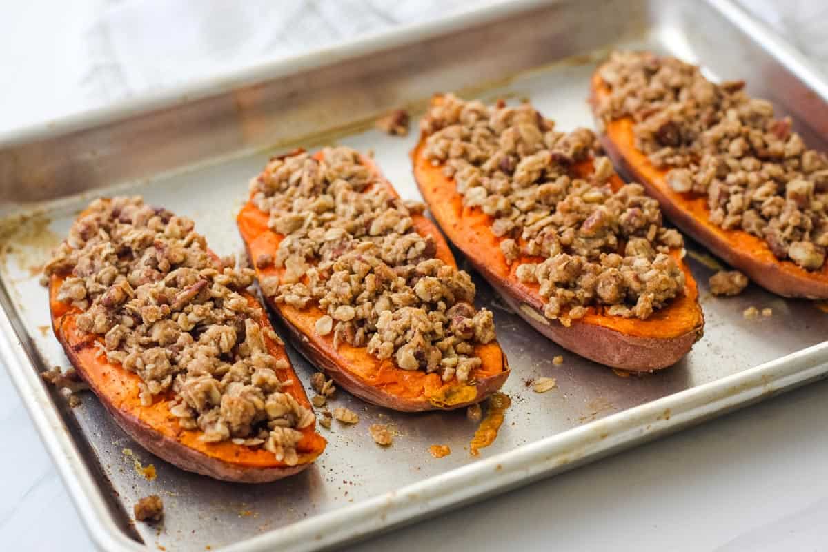 Baked sweet potato halves on a pan.