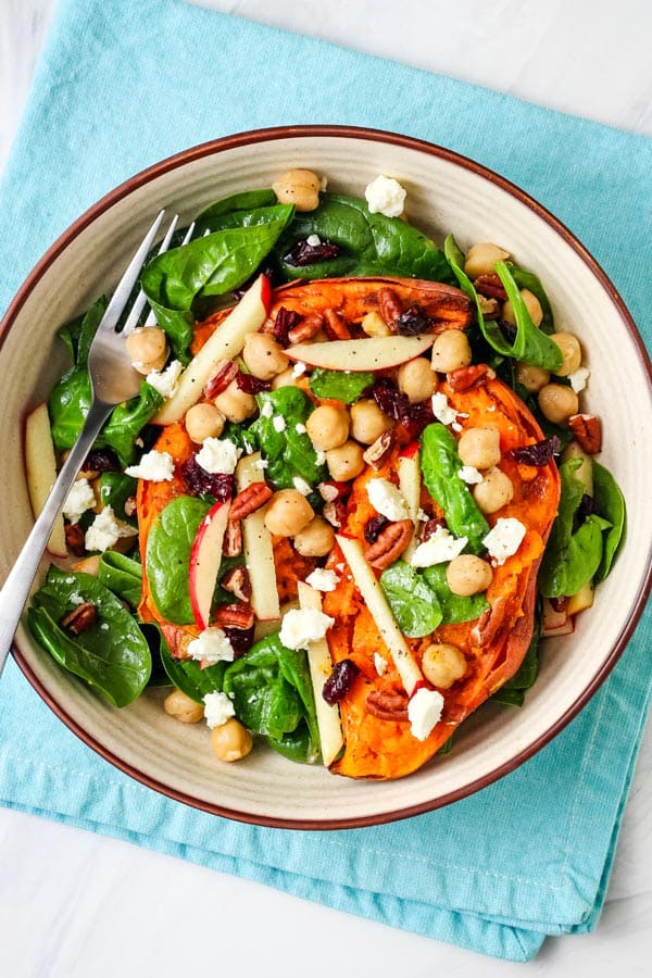 Bowl of salad and baked sweet potato halves.