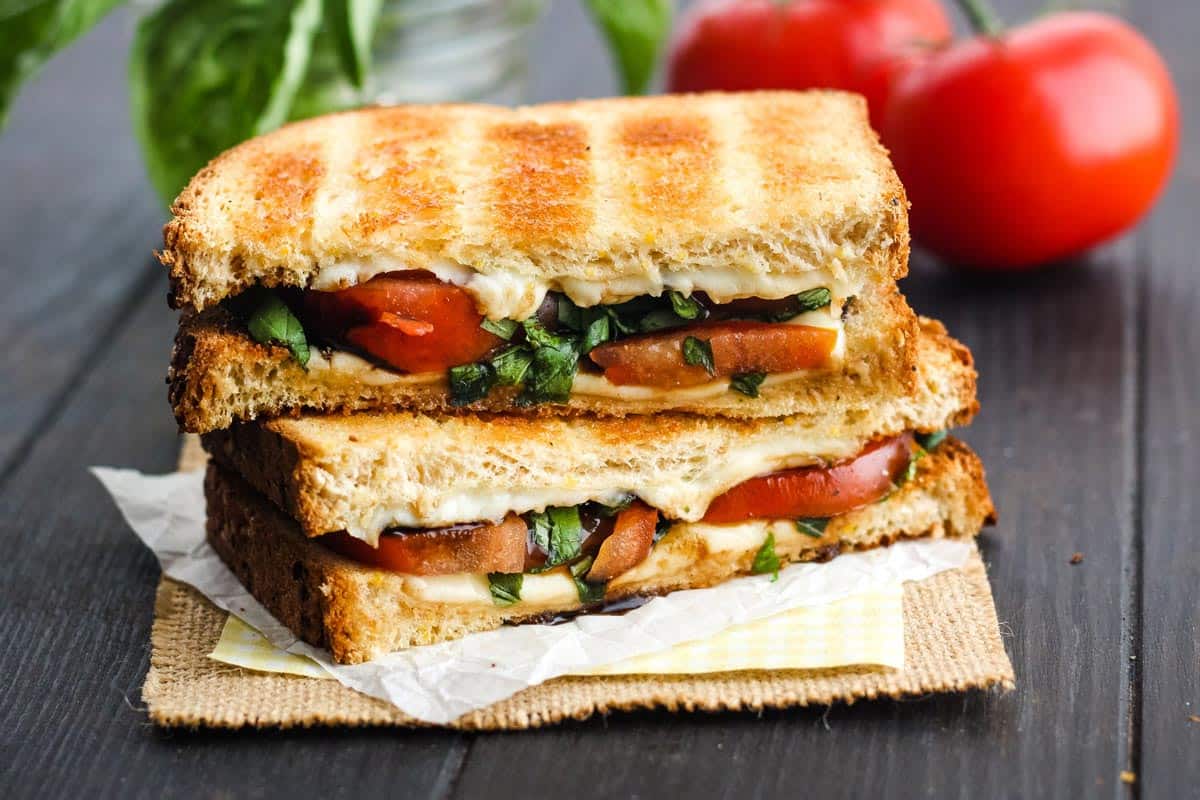 Stacked slices of tomato and cheese sandwich on a table.