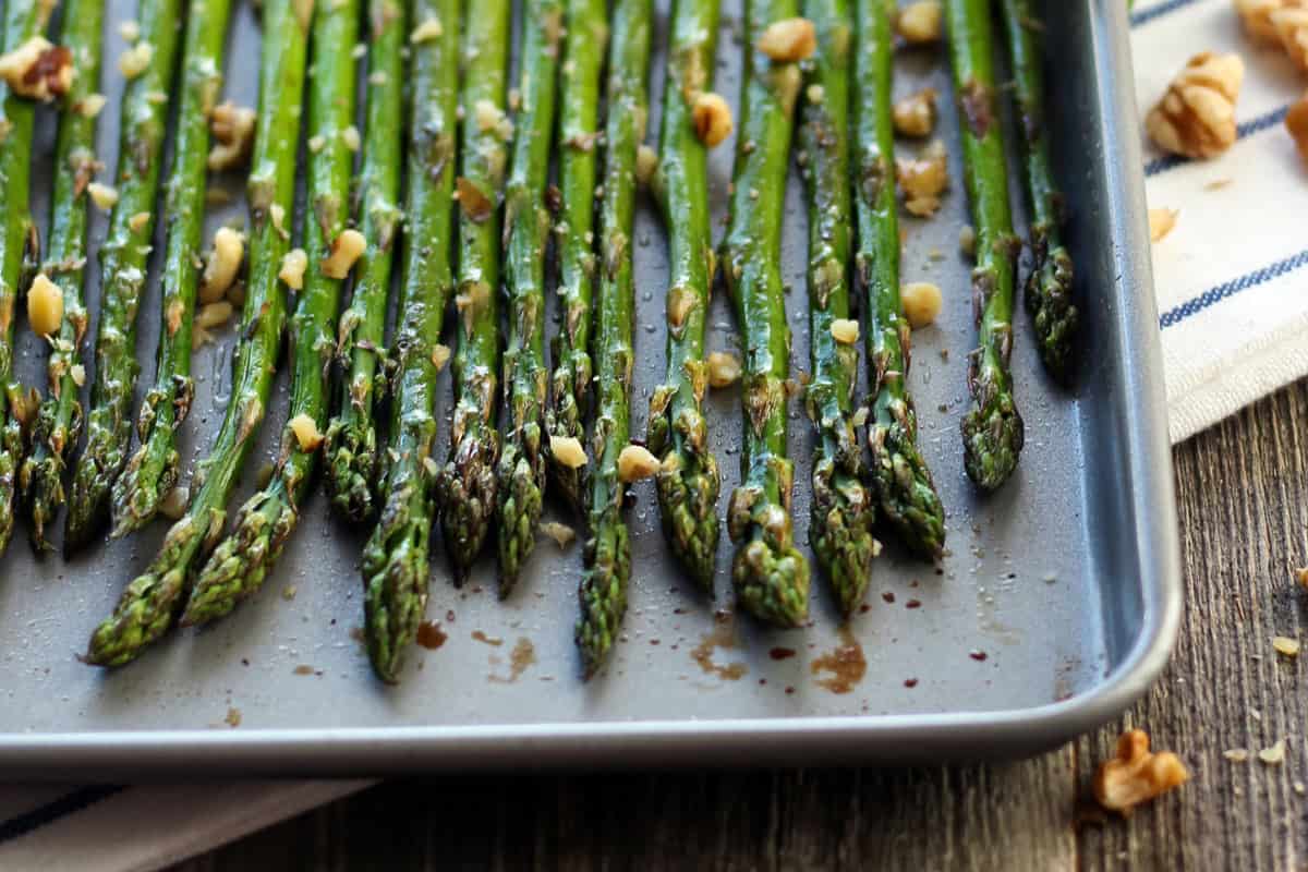 Thin spears of roasted asparagus on a small sheet pan.