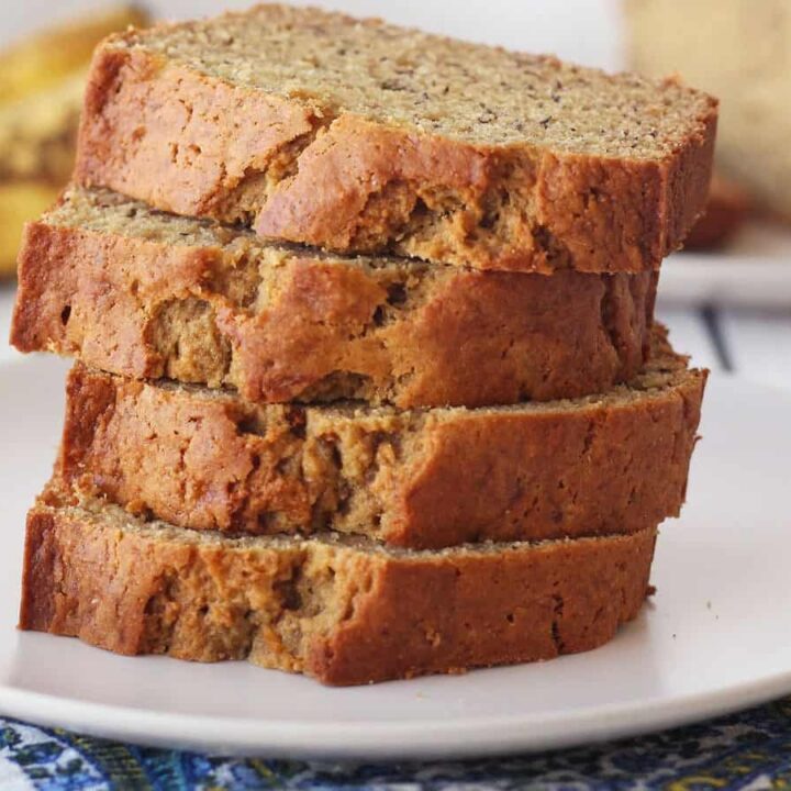 Closeup of banana bread slices stacked on a white plate.