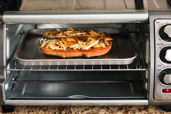 Bread rolls topped with cheese inside a toaster oven.