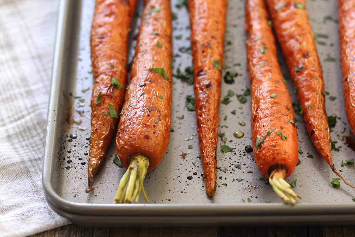 Closeup of whole roasted carrots on a pan.