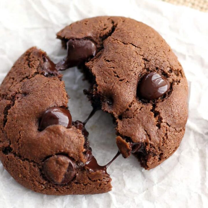 Closeup of warm chocolate cookie broken in half with melted chocolate chips spreading across the middle.