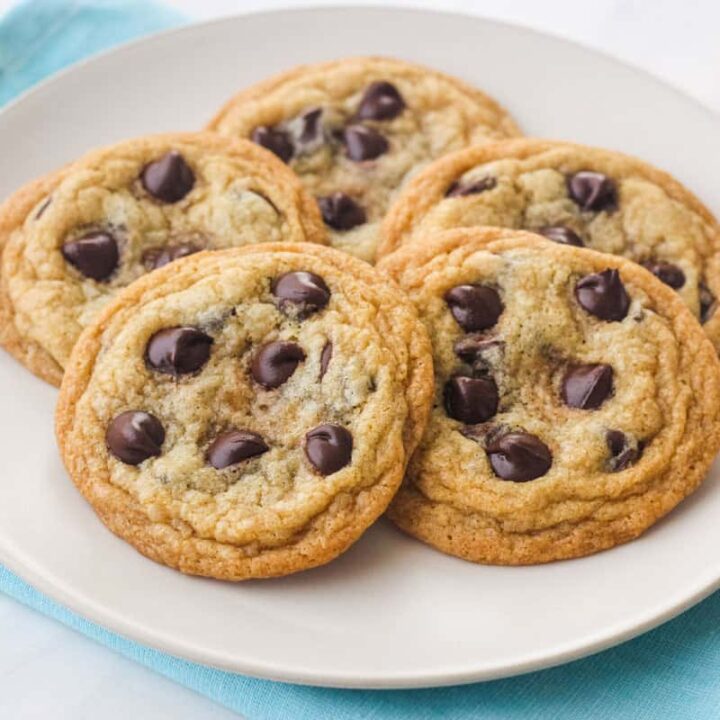 Plate of five golden brown cookies with melty chocolate chips.