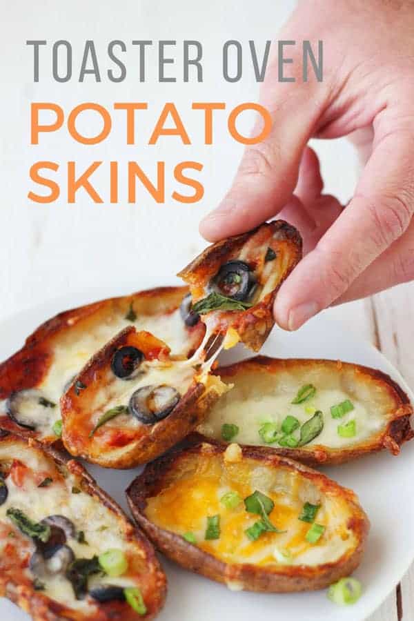 A hand pulling a cheesy piece of potato skin off of a plate.