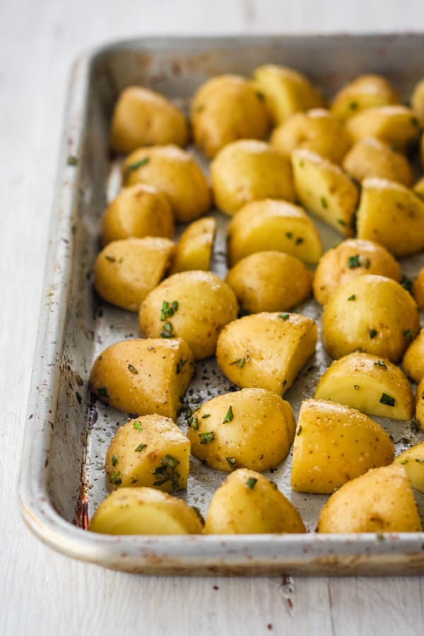 Uncooked baby potatoes on a quarter sheet pan.