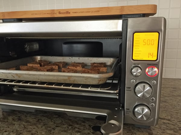 A pan of tofu in a large toaster oven with rack in the middle position.