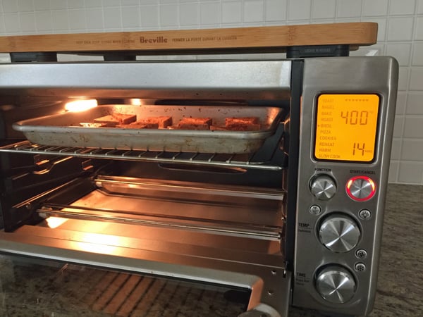 A pan of tofu in a large toaster oven with the rack in the top position.