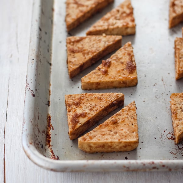 Tofu triangles on an oiled rimmed baking sheet.