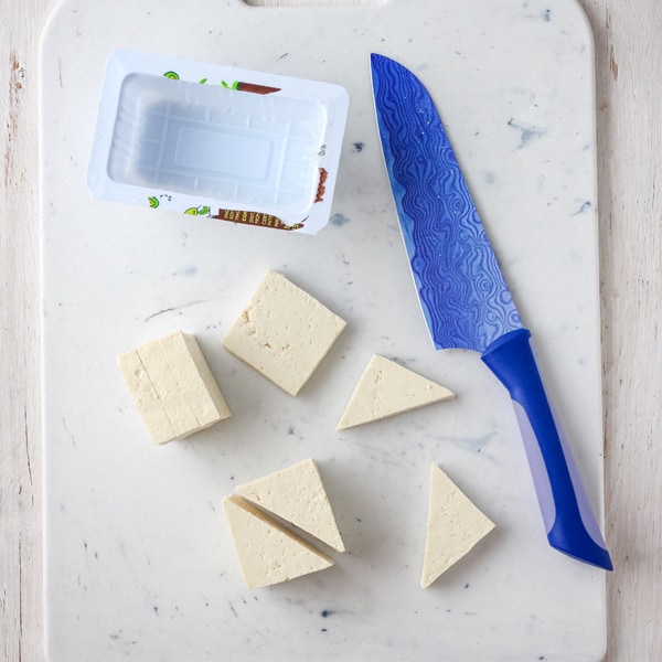 Drained tofu sliced into triangles on a cutting board.