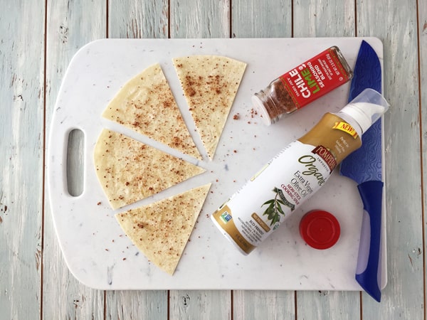 A seasoned and oiled tortilla sliced into wedges on a cutting board.