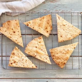 Baked tortilla chips cooling on a toaster oven cooking rack.