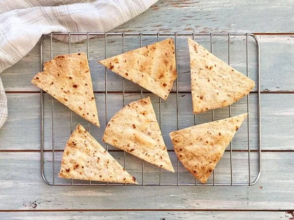 Baked tortilla chips cooling on a toaster oven cooking rack.