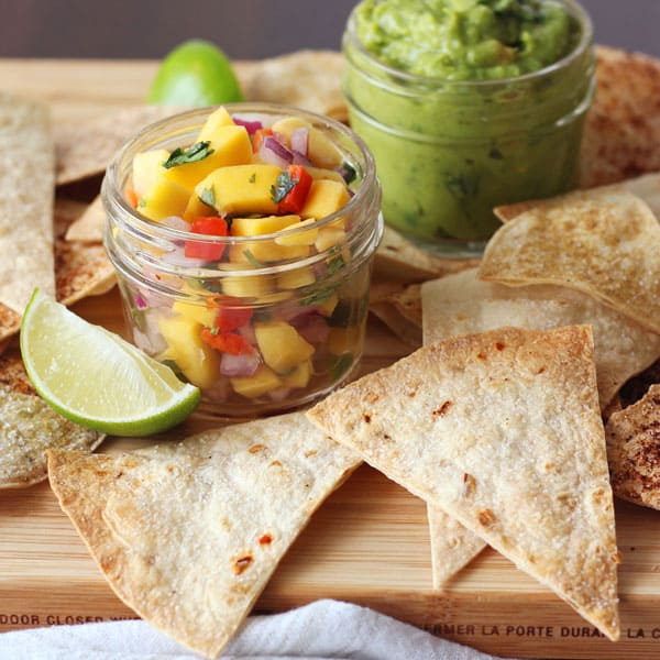 Baked tortilla chips on a platter with mango salsa and guacamole.