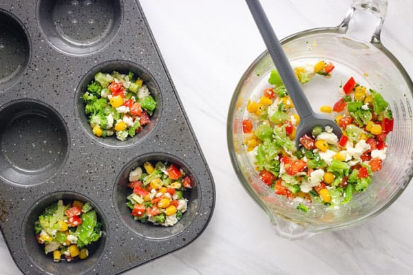 Mixed veggies and feta scooped into a muffin tin.