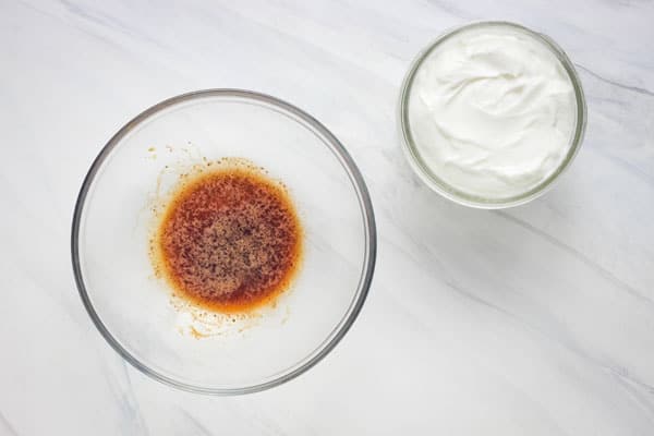 Small bowl of instant espresso liquid next to a container of yogurt.