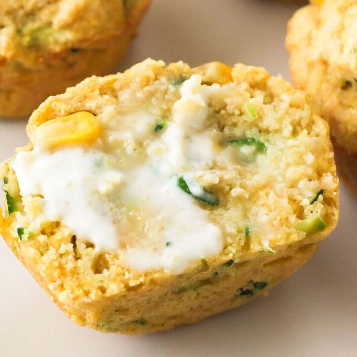 Closeup of half a warm corn muffin spread with butter.